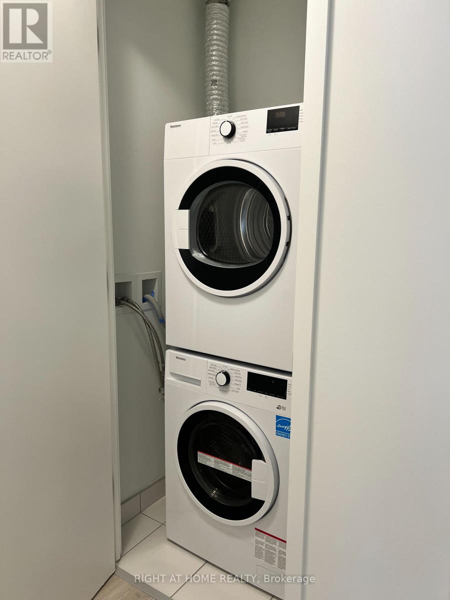 A white washing machine with the door open is in a small space.