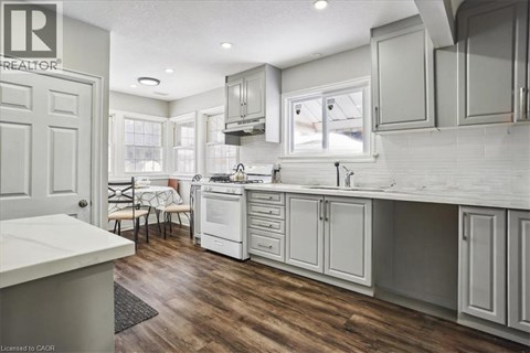 A kitchen with white cabinets and a wooden floor.