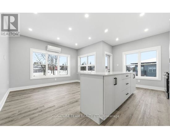 A spacious, well-lit kitchen and living room with a view of the outdoors through the windows.