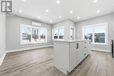 A spacious, well-lit kitchen and living room with a view of the outdoors through the windows.
