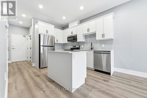 A modern kitchen with white cabinets and stainless steel appliances.