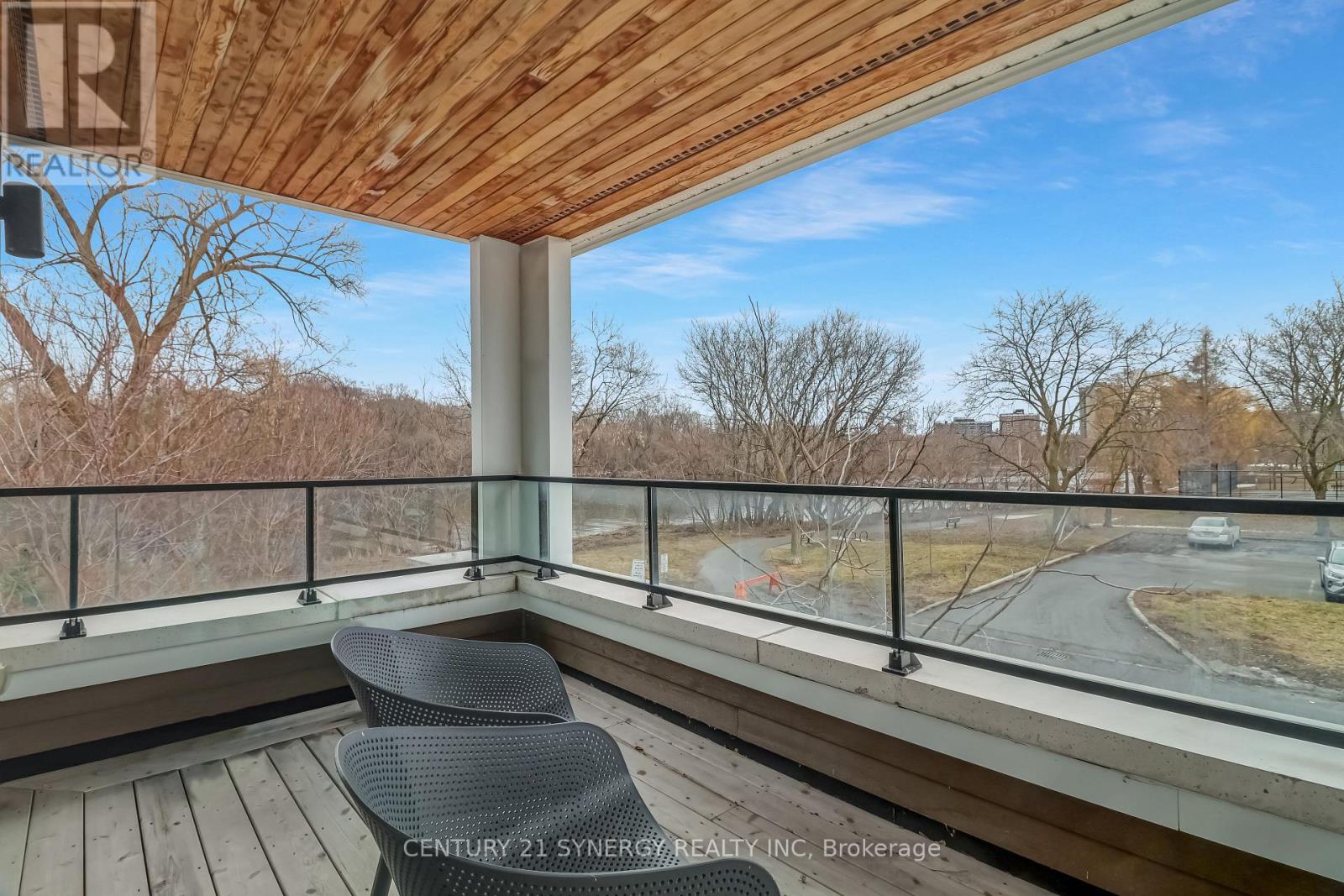 A balcony with a chair and a view of a road and trees.