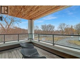 A balcony with a chair and a view of a road and trees.
