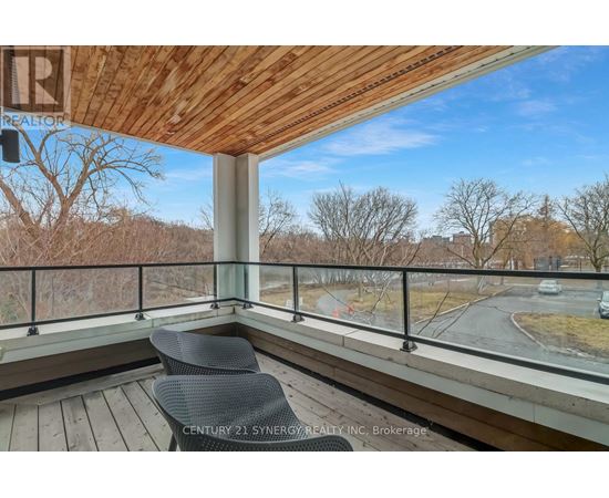 A balcony with a chair and a view of a road and trees.