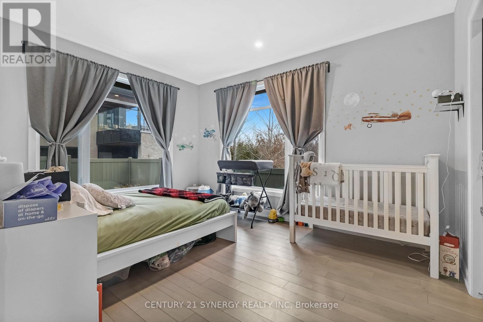 A bedroom with a bed, a crib, and a window with curtains.
