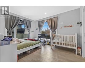 A bedroom with a bed, a crib, and a window with curtains.