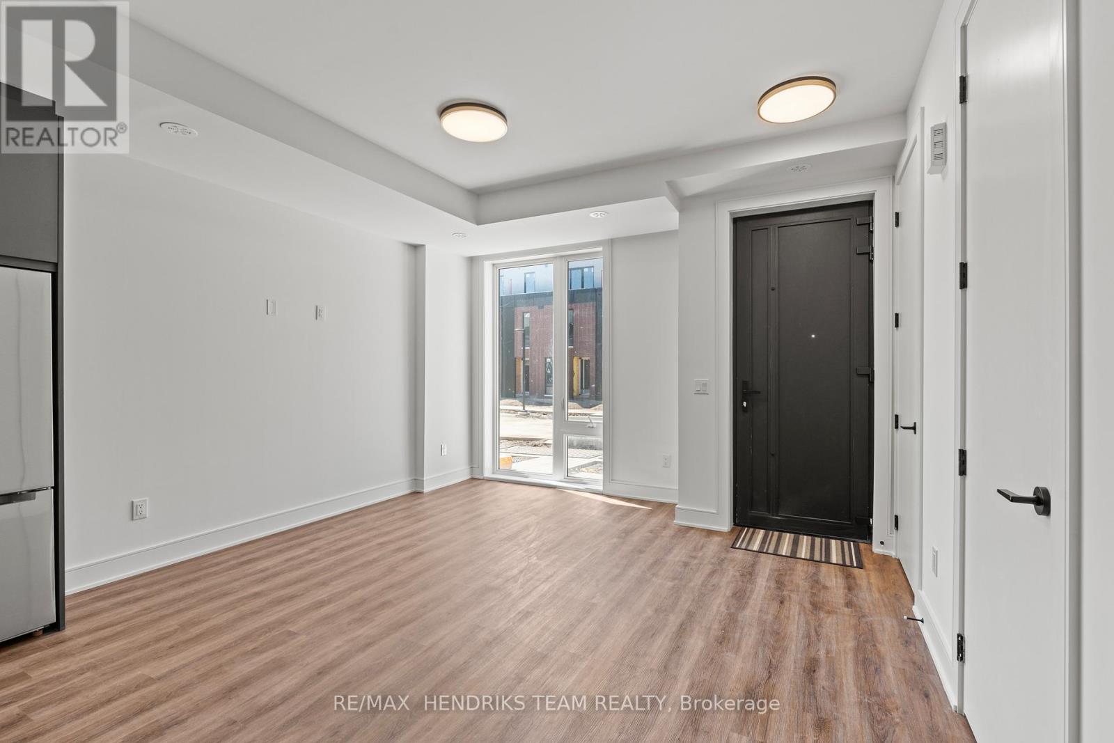 A spacious room with wooden flooring and white walls.