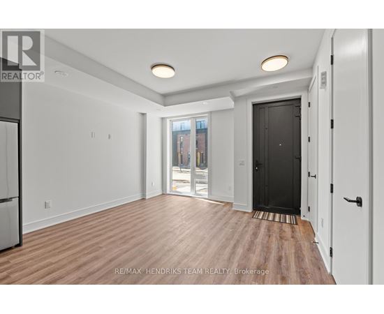 A spacious room with wooden flooring and white walls.