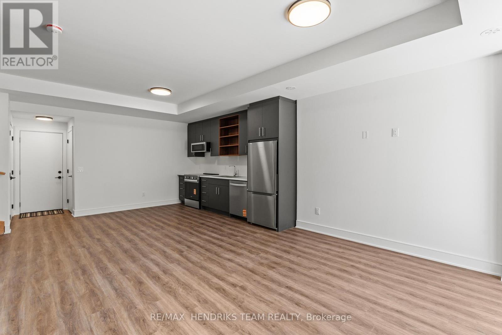 A spacious room with a kitchenette and wooden flooring.