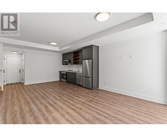 A spacious room with a kitchenette and wooden flooring.