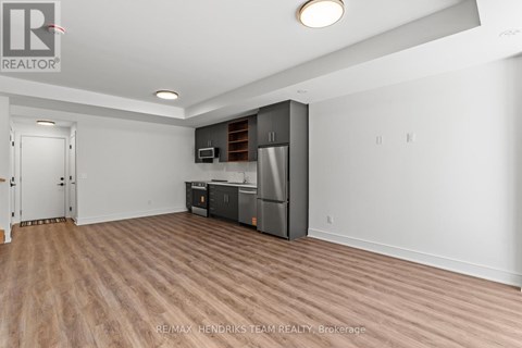 A spacious room with a kitchenette and wooden flooring.