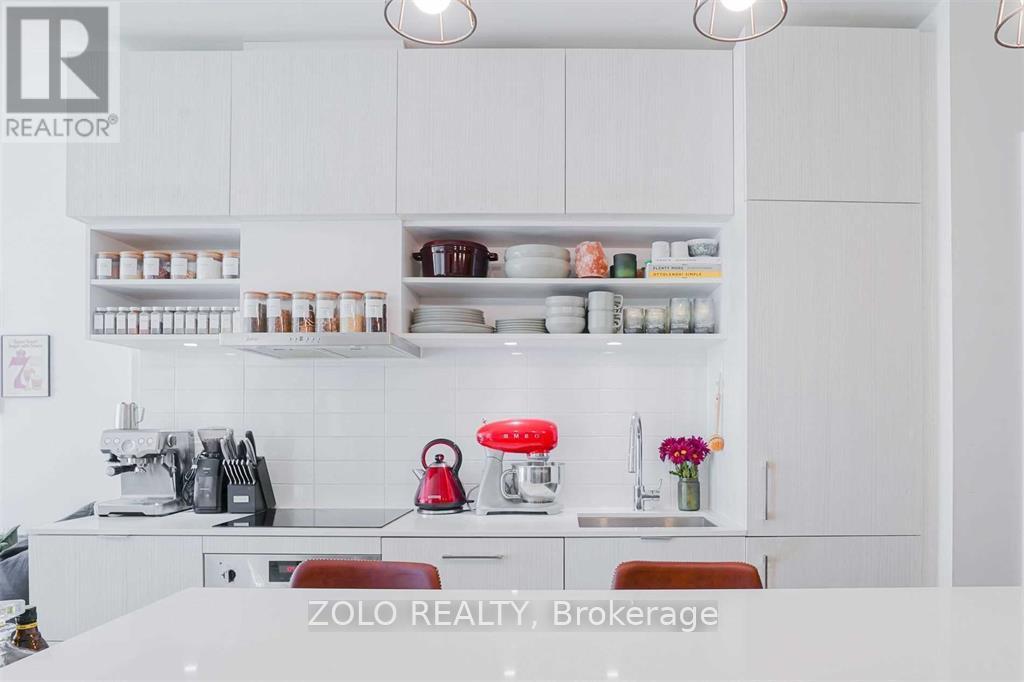 A modern kitchen with white cabinets and a red stove top.