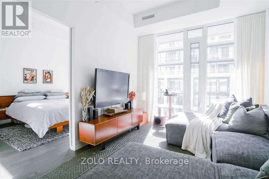 A well-lit bedroom with a large bed and a flat-screen TV.