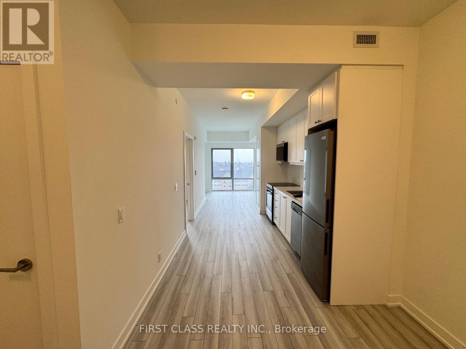 A long hallway with wood floors and white walls.