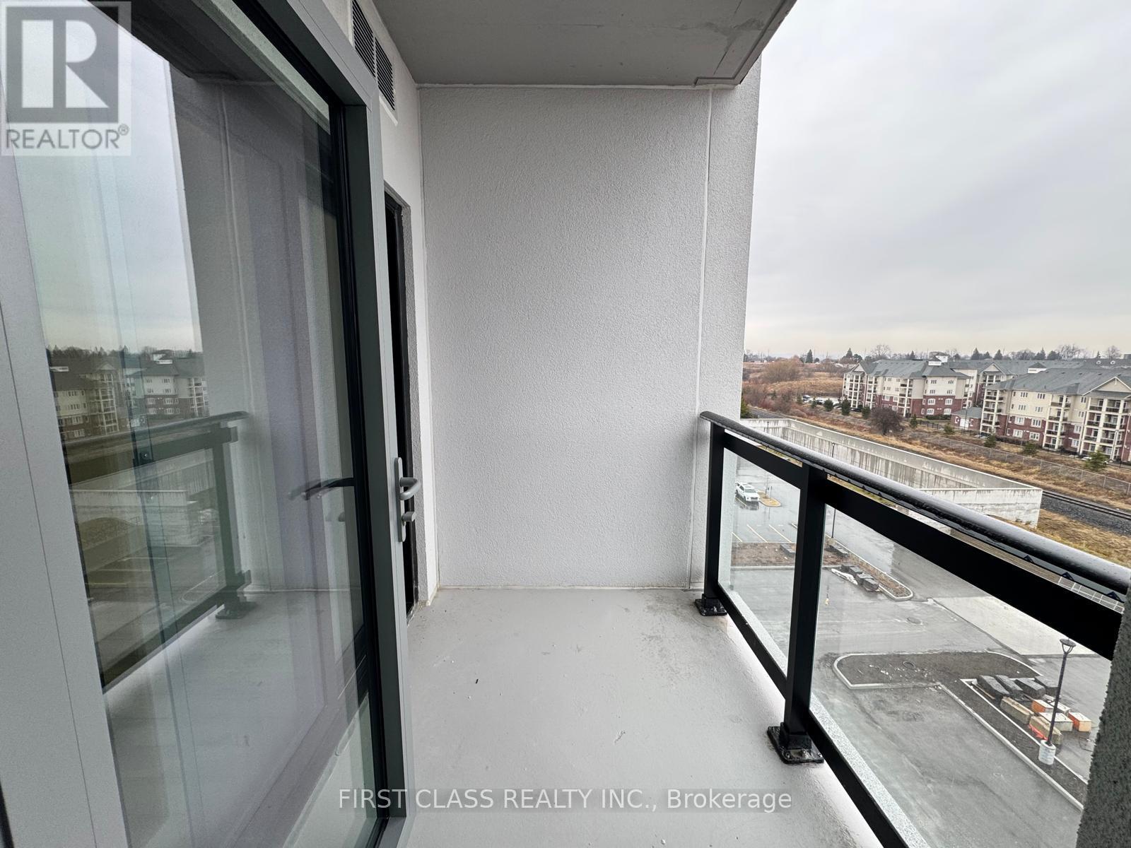 A balcony with a view of a parking lot and buildings.