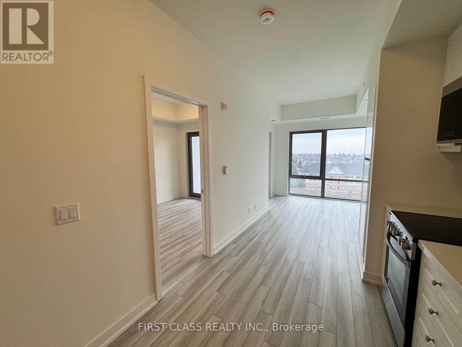 A real estate company's logo is on the wall of a spacious room with wood flooring and a large window.