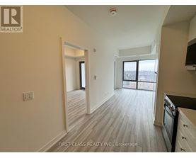 A real estate company's logo is on the wall of a spacious room with wood flooring and a large window.