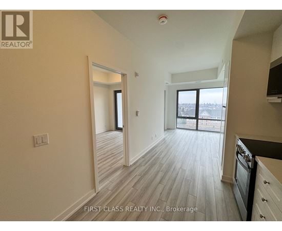 A real estate company's logo is on the wall of a spacious room with wood flooring and a large window.