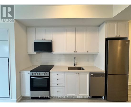 A kitchen with white cabinets and a black microwave above the stove.