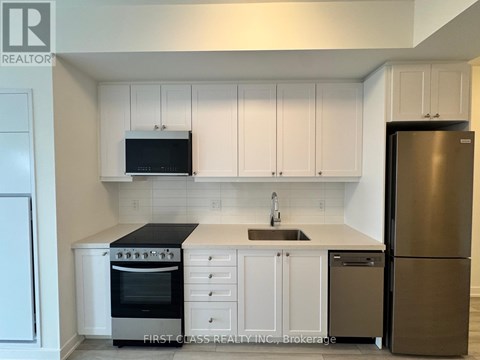 A kitchen with white cabinets and a black microwave above the stove.