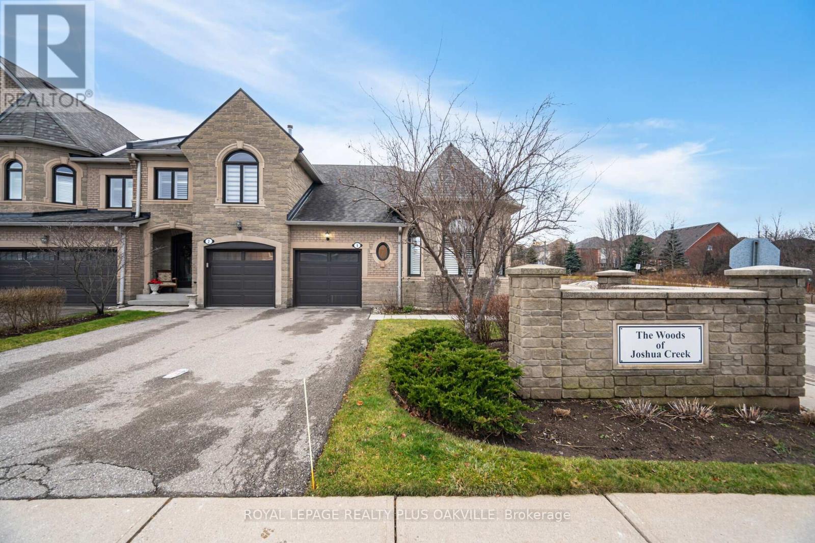 A large house with a sign that says "The Woods Joshua Creek" in front of it.