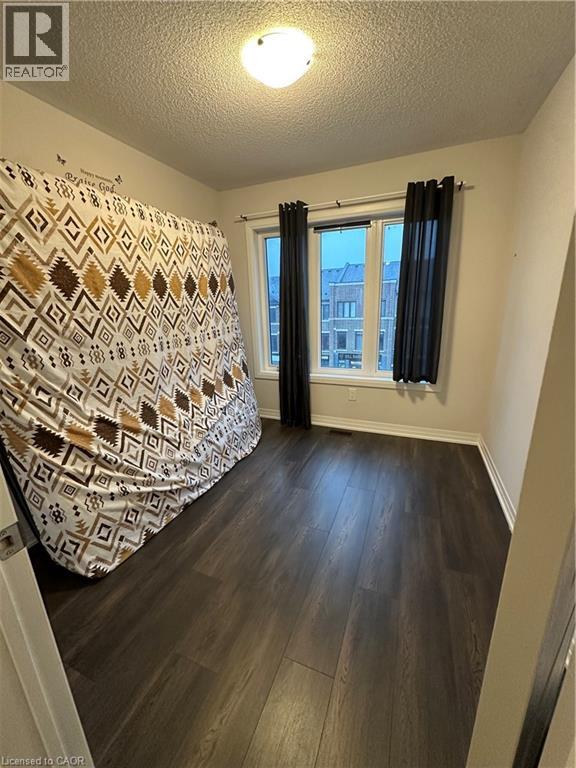 A bedroom with a patterned bedspread and a window with black curtains.