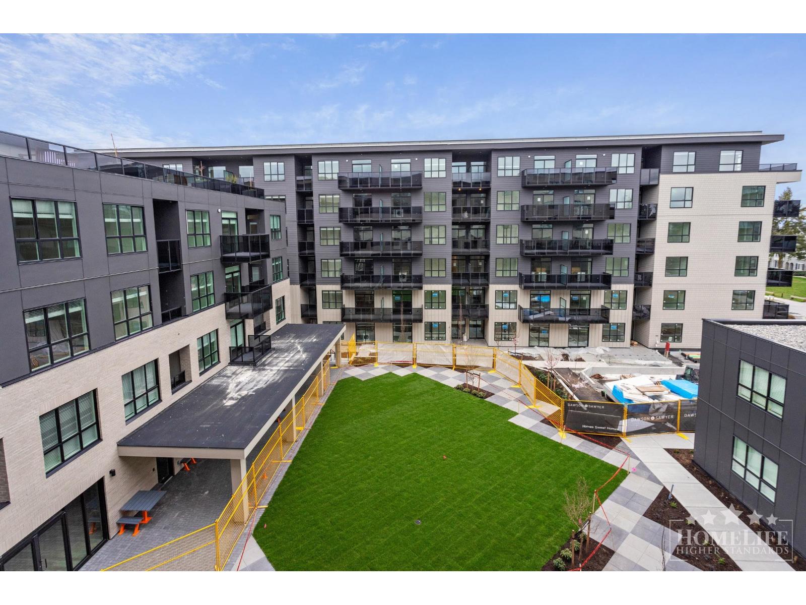 A large grassy area in front of a building with a pool.