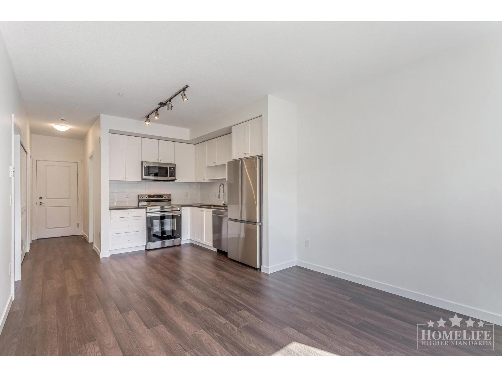 A kitchen with white cabinets and a stainless steel refrigerator.