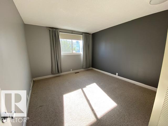A room with a carpeted floor and a window with curtains.