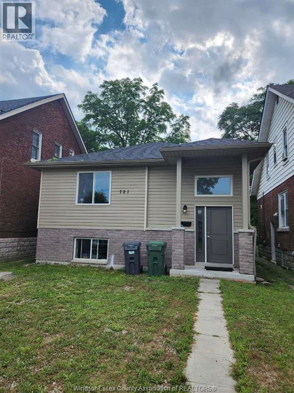 A house with a grey front door and a green trash bin.