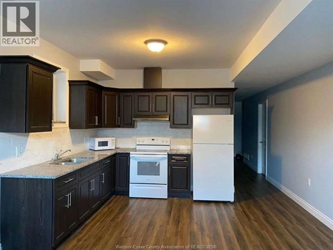 A kitchen with dark wood cabinets and a white fridge.