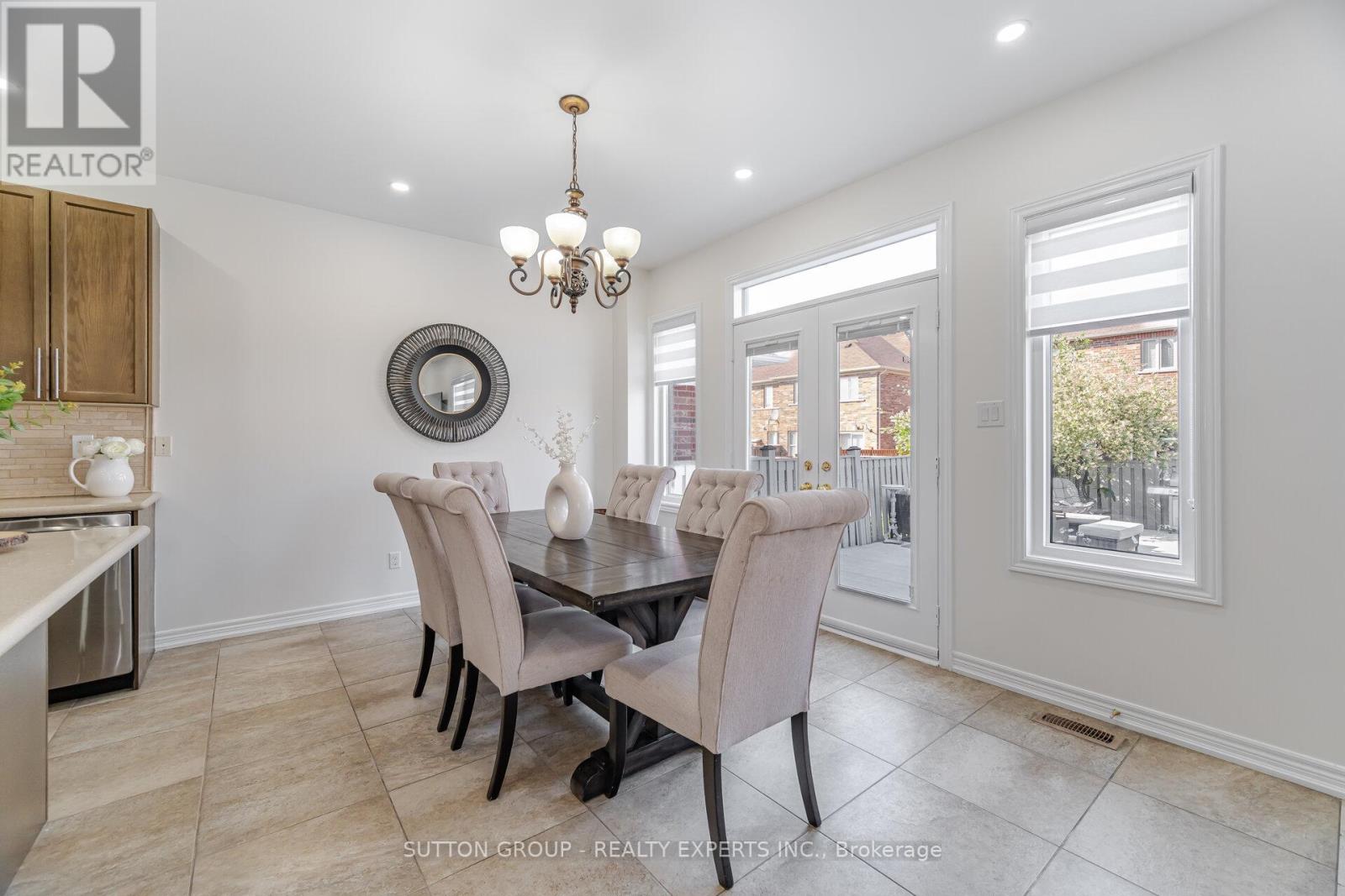 A dining room with a table set for six with a chandelier hanging above.