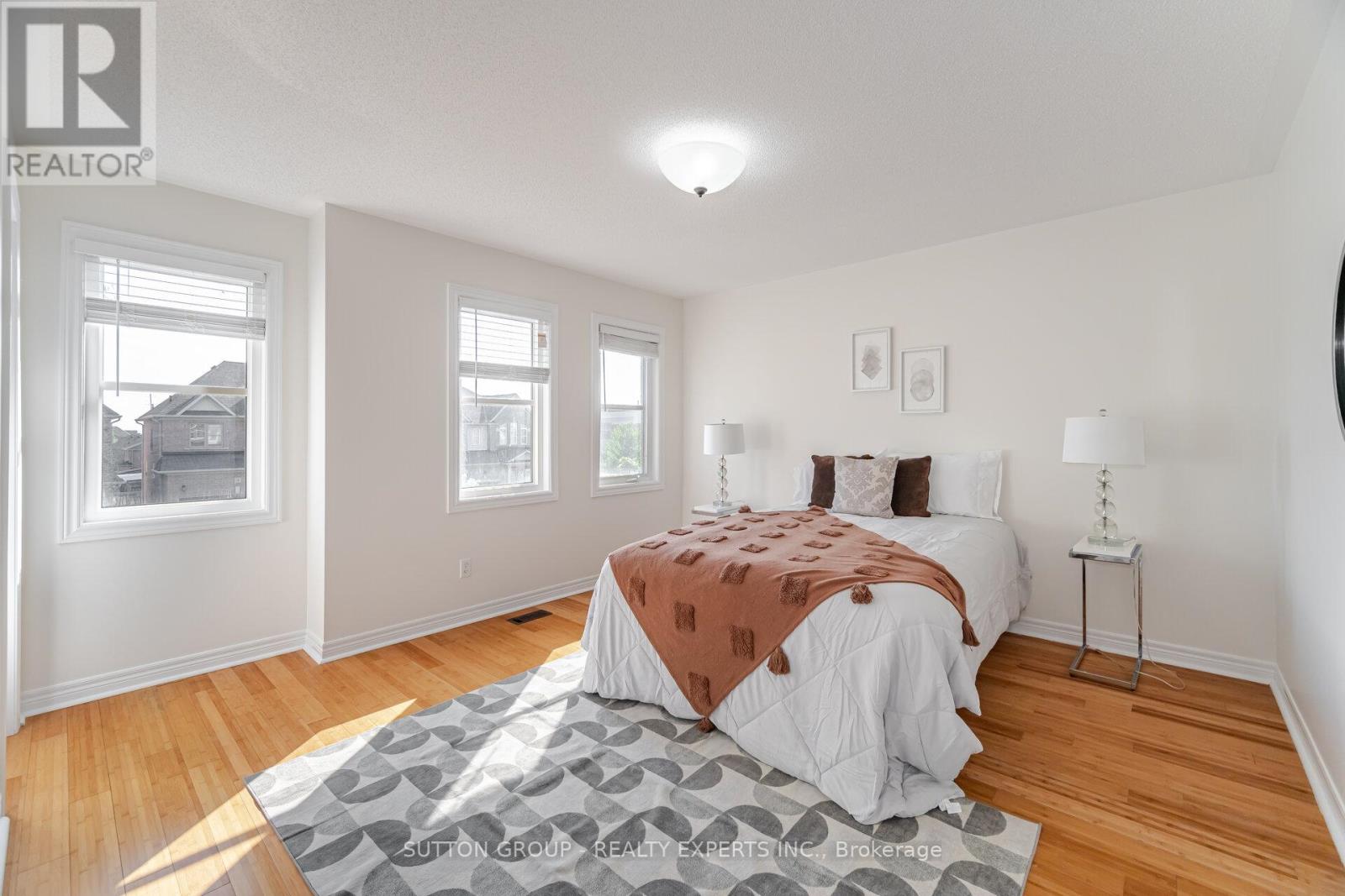 A bedroom with a bed, two windows, and a rug on the floor.
