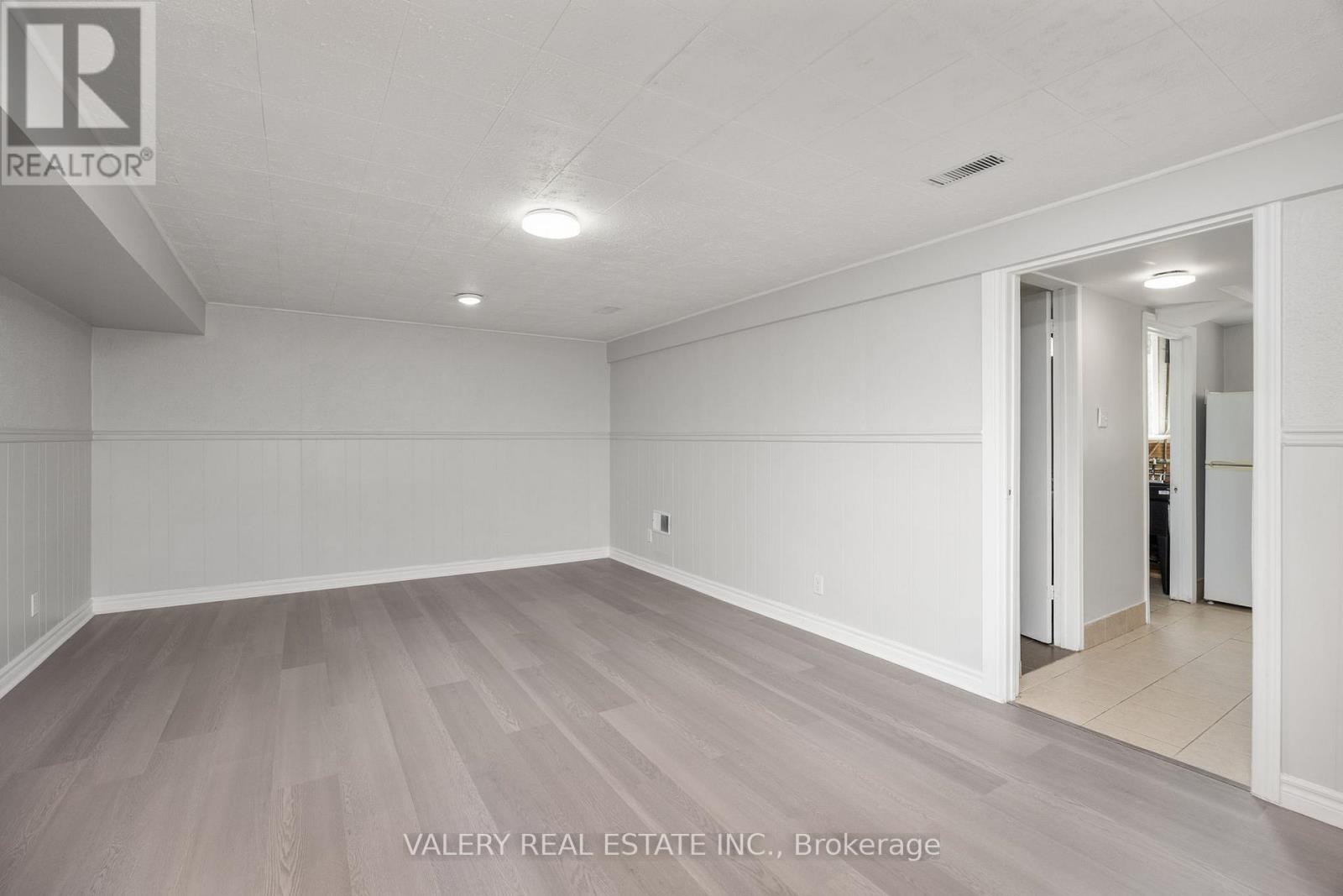 A spacious room with wood flooring and white walls.