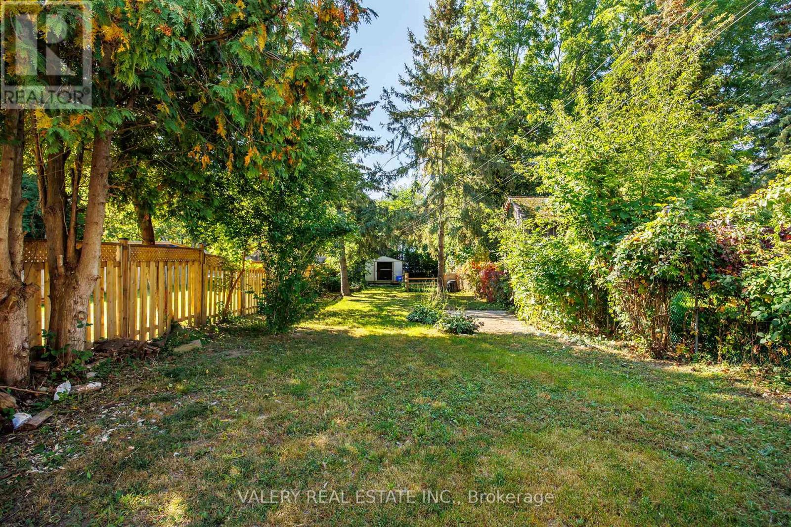 A yard with a fence and trees.
