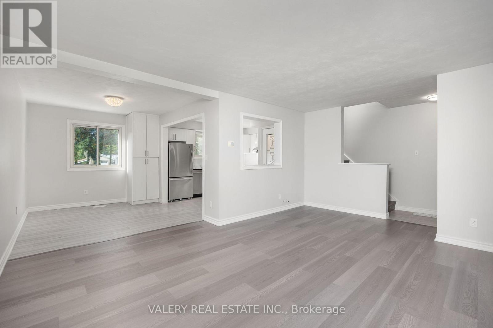 A spacious, empty room with wood flooring and white walls.