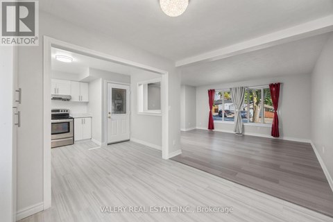 A spacious room with a kitchen area and a living room with a couch and a window.