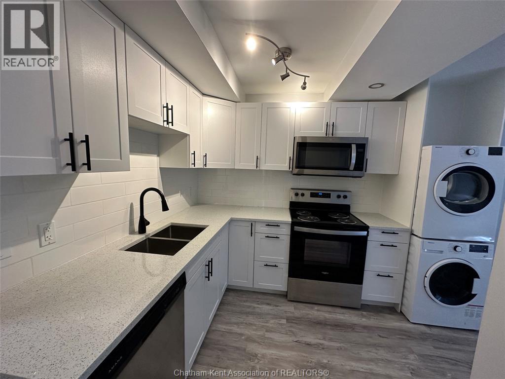 A kitchen with white cabinets and a black countertop.