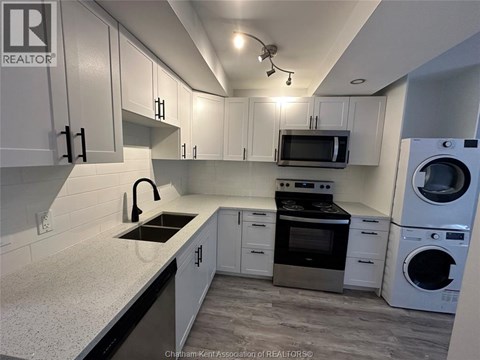 A kitchen with white cabinets and a black countertop.