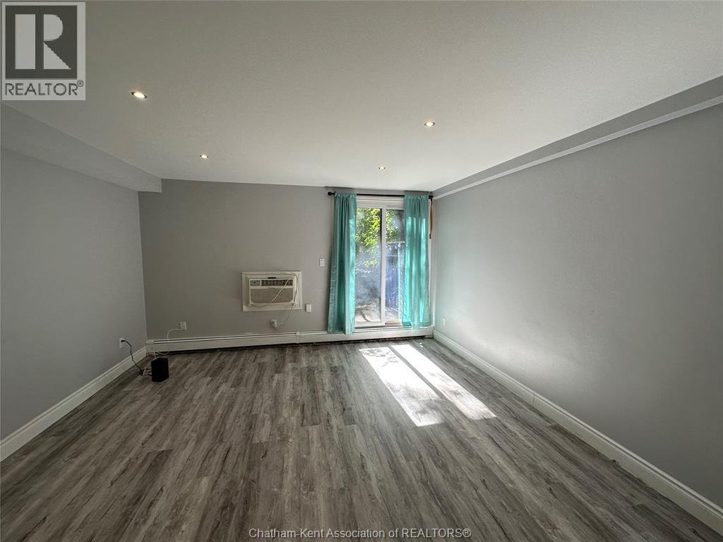 A room with wooden flooring and a window with a view of trees outside.