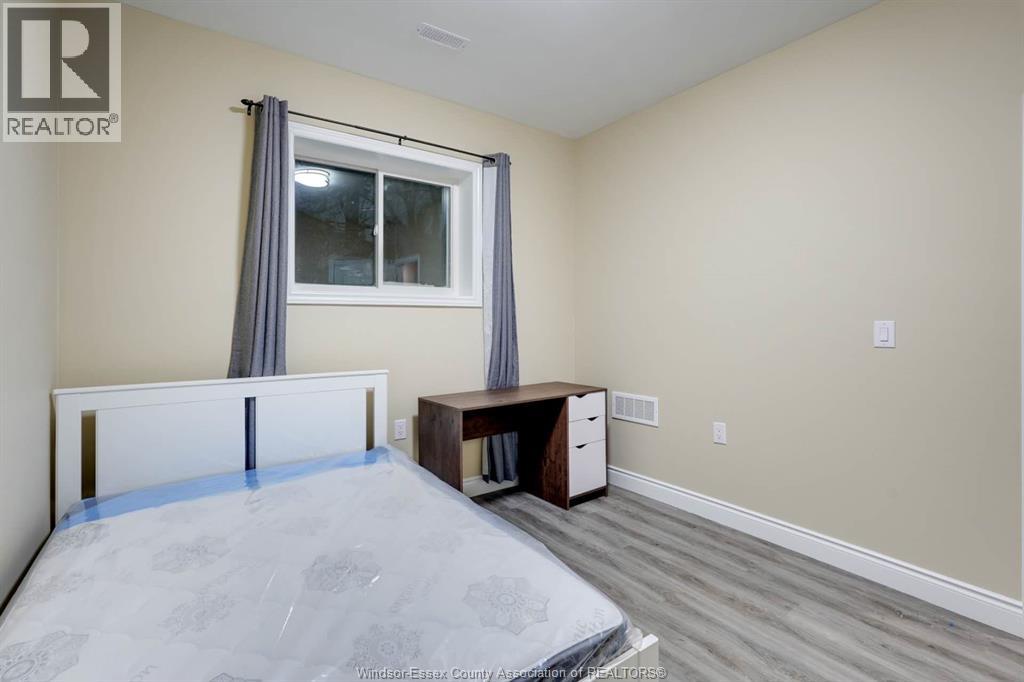 A bedroom with a bed, desk, and window.