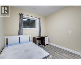 A bedroom with a bed, desk, and window.