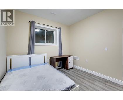 A bedroom with a bed, desk, and window.