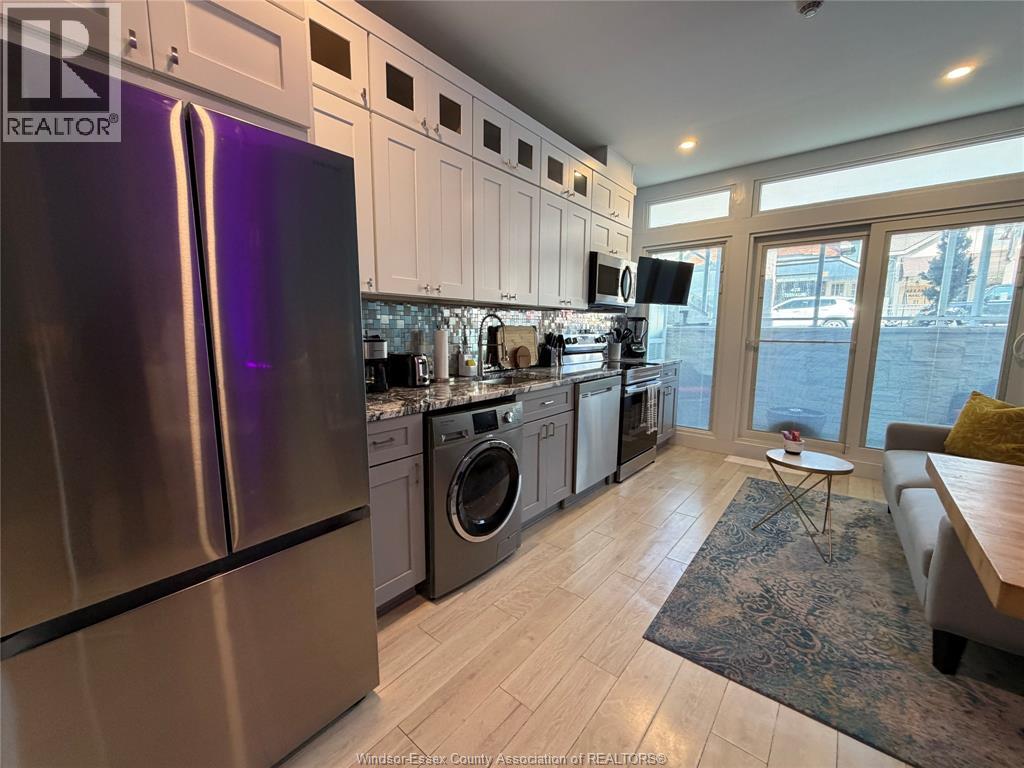 A kitchen with a refrigerator, washing machine, and a dining table.