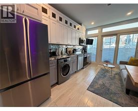 A kitchen with a refrigerator, washing machine, and a dining table.