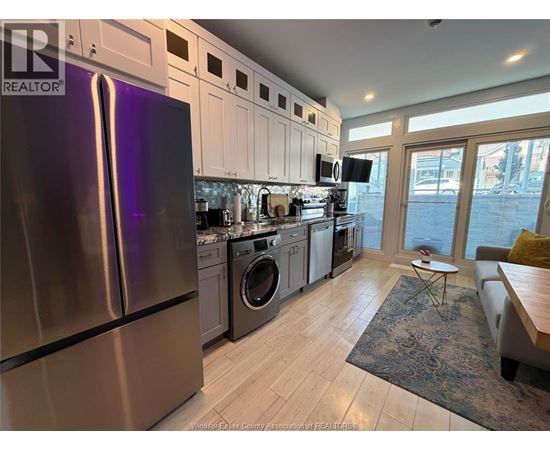A kitchen with a refrigerator, washing machine, and a dining table.