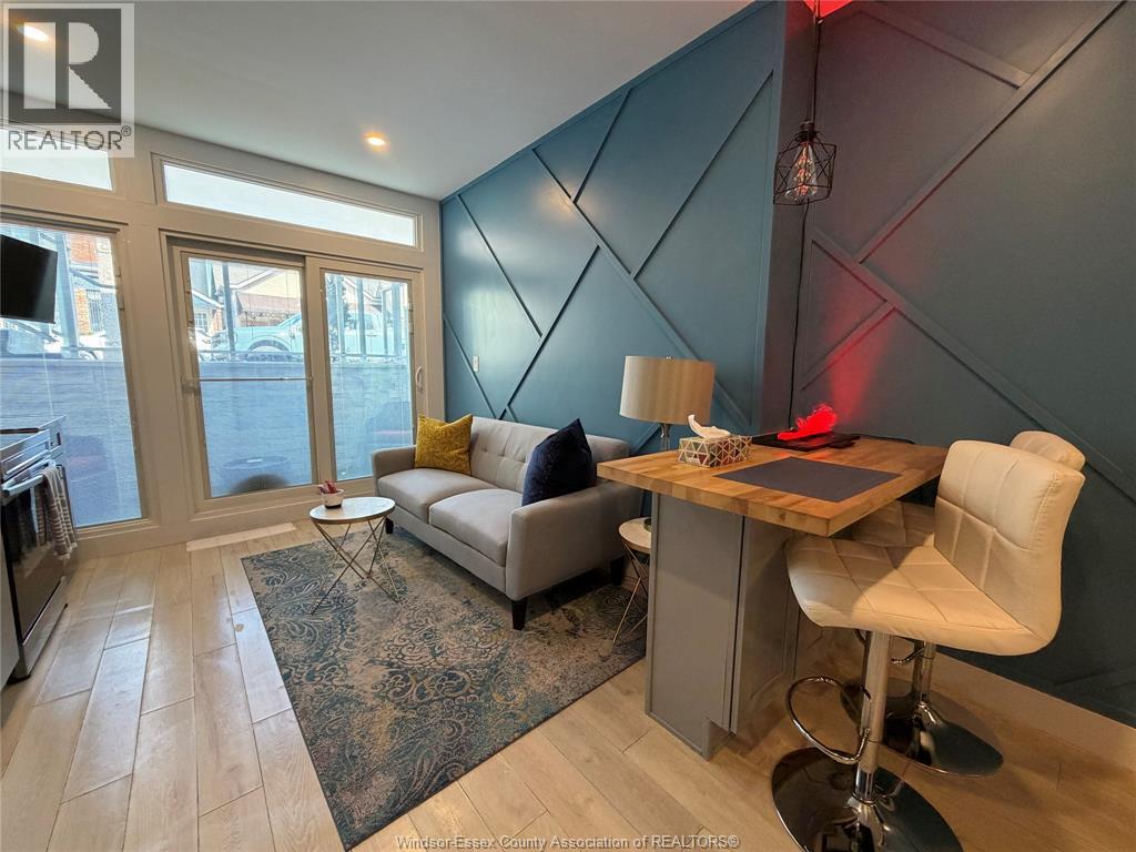 A living room with a grey couch, a white chair, and a wooden desk.