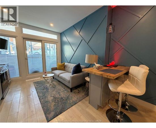 A living room with a grey couch, a white chair, and a wooden desk.