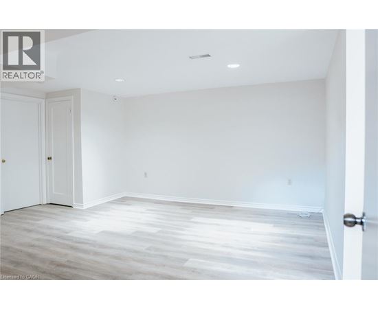 A spacious room with a wooden floor and white walls.