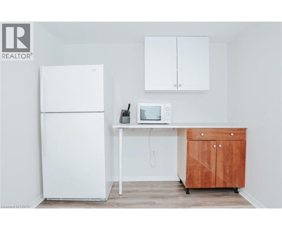 A white refrigerator is in a kitchen next to a wooden cabinet.